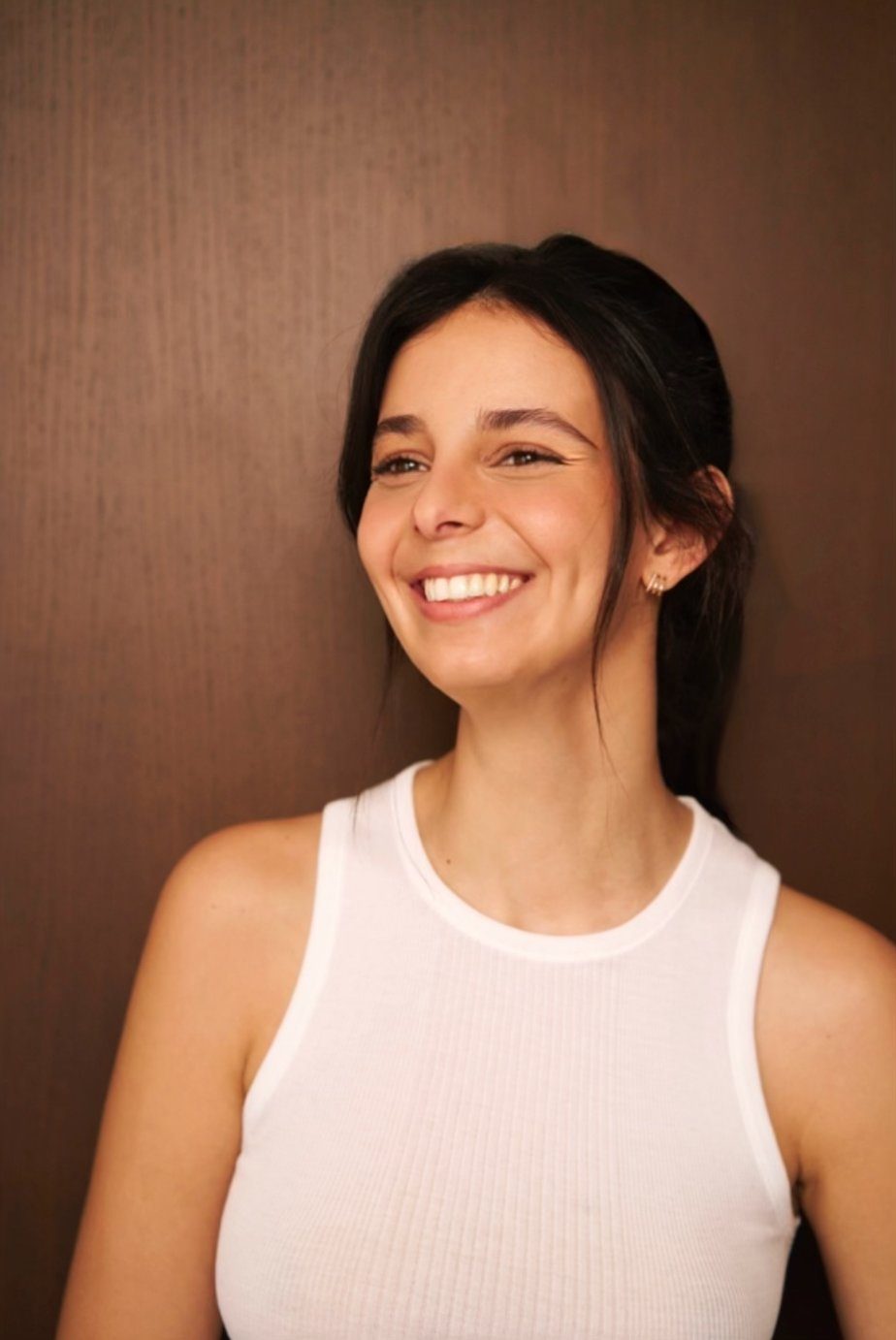 Yasmin riant, débardeur blanc, fond bois